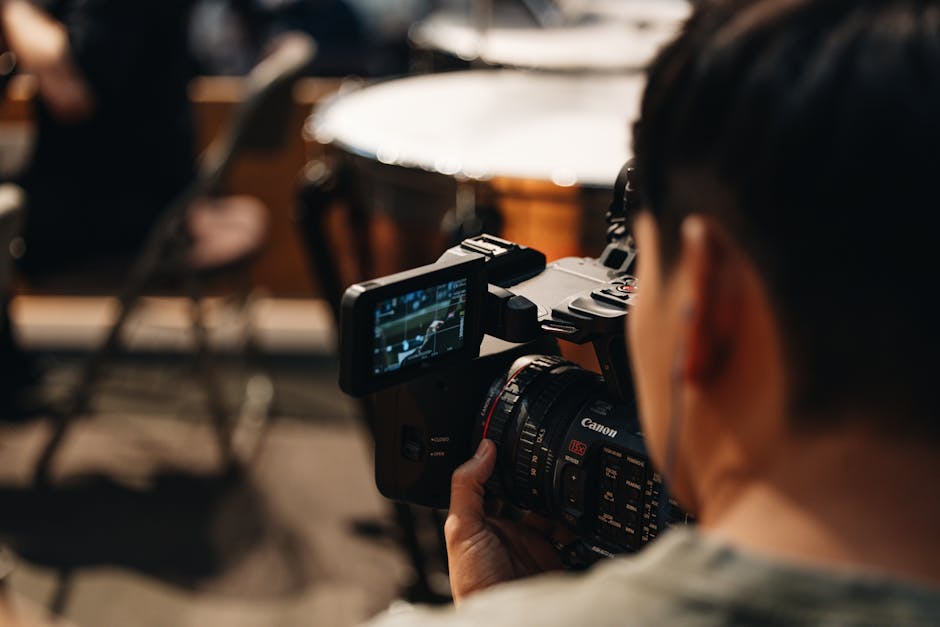 Filmmaker focuses intently as they capture video using a Canon camera in a studio setting.
