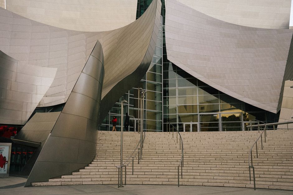 A close-up view of a unique curved metal facade of a performing arts center with a staircase.