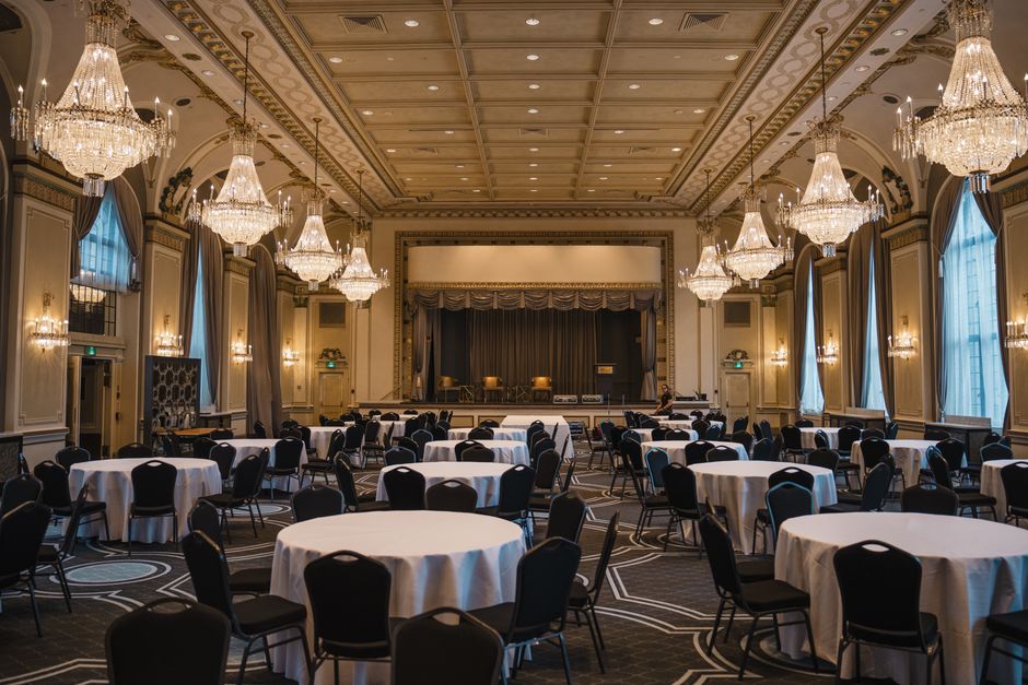Luxurious empty banquet hall in Québec featuring round tables, elegant chandeliers, and classical architecture.