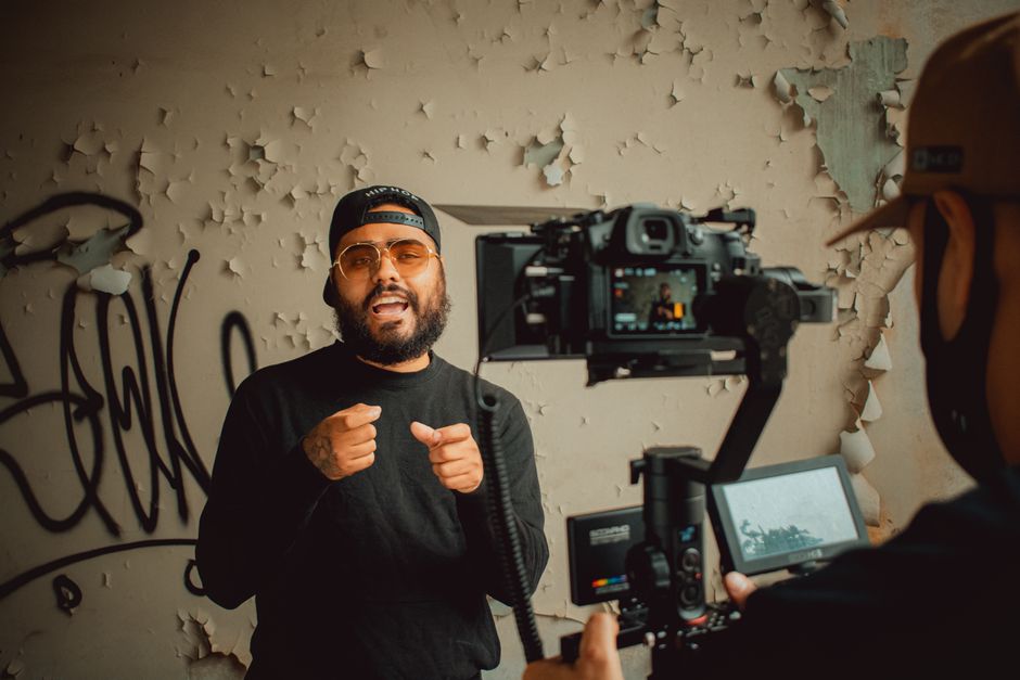 Hip-hop artist passionately performing during an indoor music video recording session.