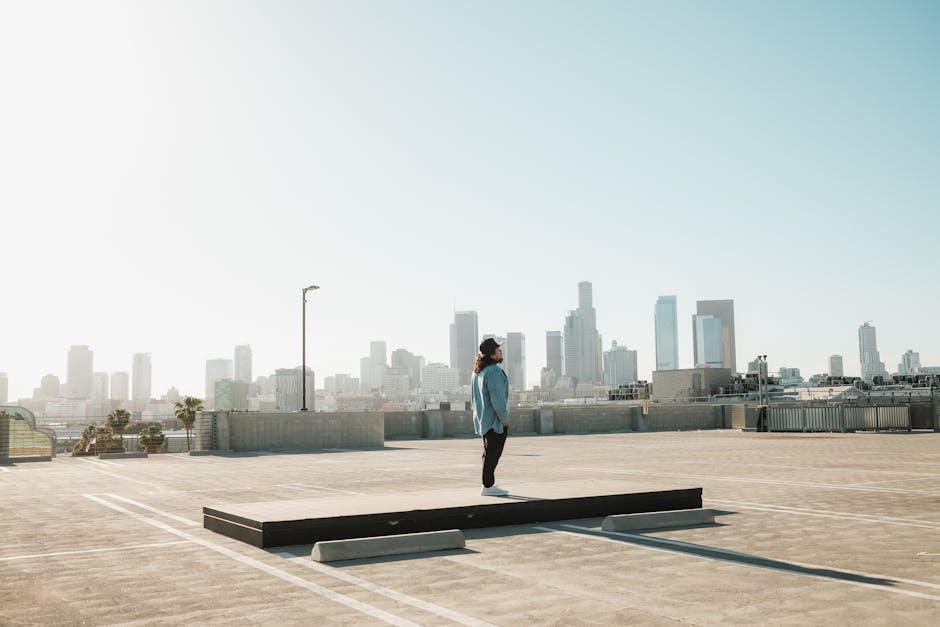 A lone individual on a rooftop with a stunning view of the Los Angeles skyline under clear skies.