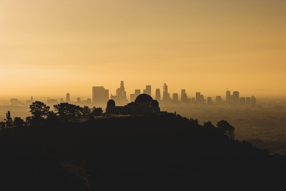 Silhouette of Griffith Observatory and Los Angeles skyline against a dramatic sunset.