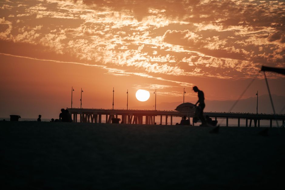 Captivating beach sunset with silhouettes in Los Angeles, featuring a golden sky and scenic pier.