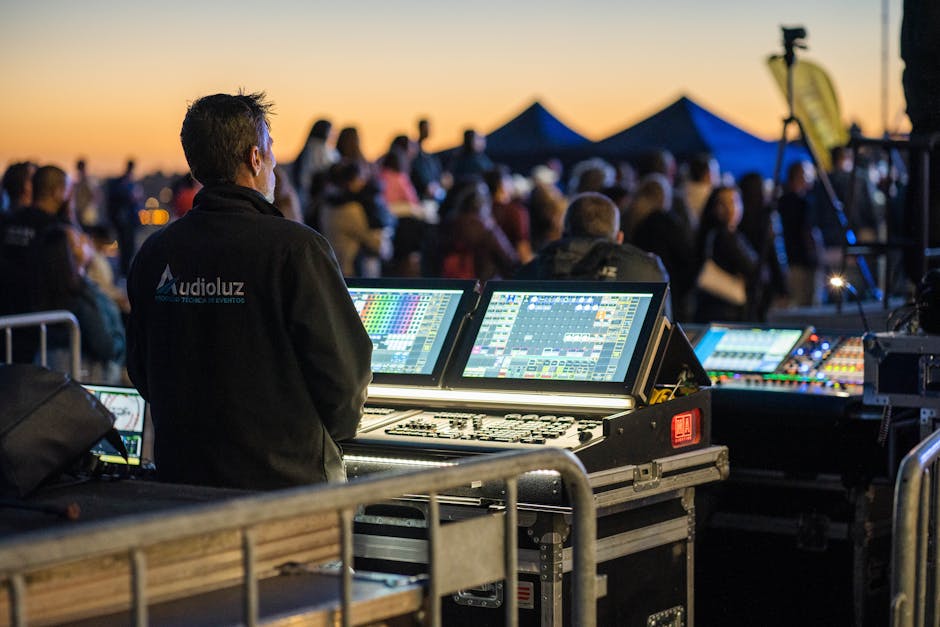Technician managing sound and lighting panels during an outdoor event at sunset.